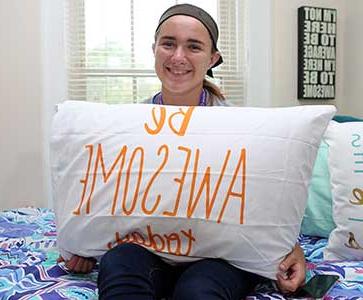 十大足球买球推荐学院的学生在她的宿舍里拿着一个枕头 